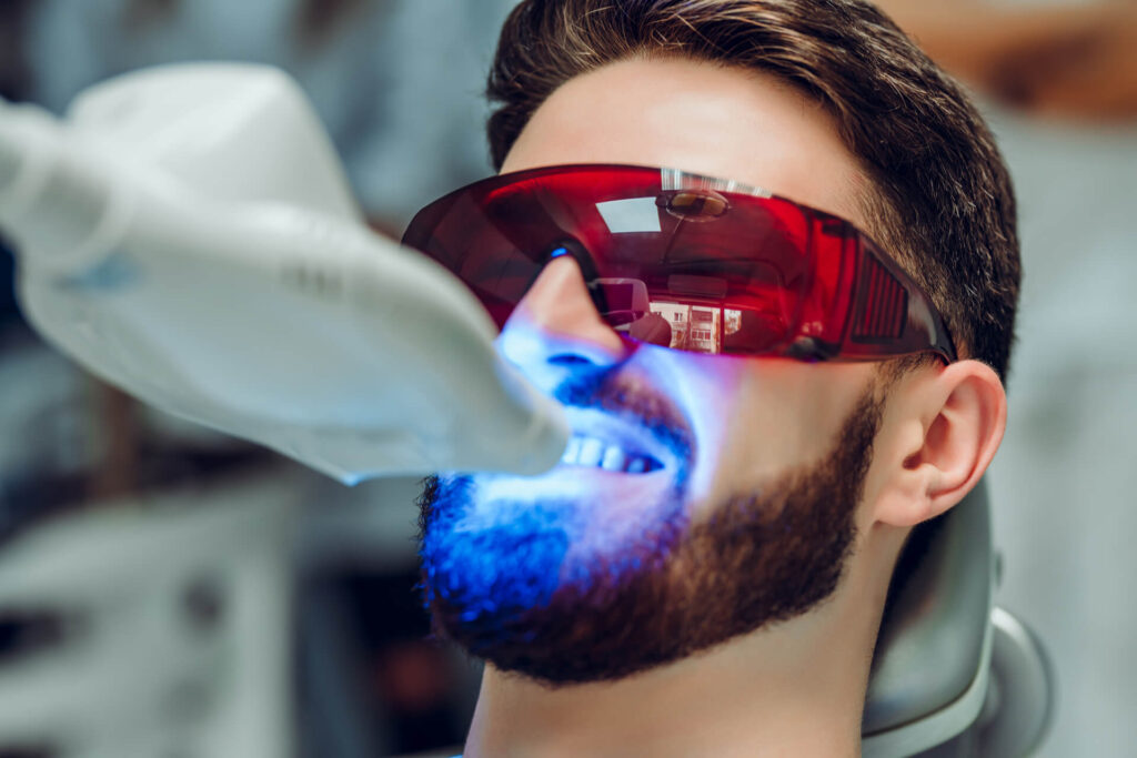 Man having teeth whitening by dental UV whitening device